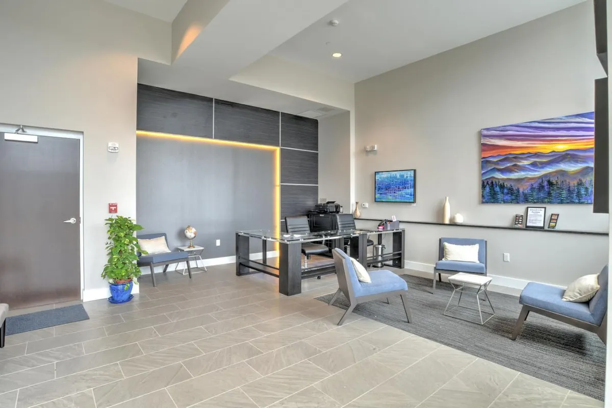 A modern, stylish workspace with a contemporary desk, unique artwork on the wall, and a comfortable seating area. The space feels open and sophisticated, encouraging creativity and relaxation.