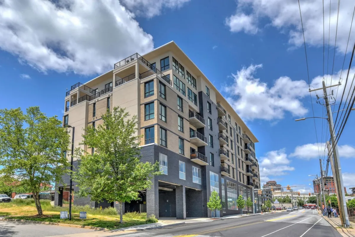 A broader view of the building’s modern architecture, showcasing balconies, green trees, and the inviting streetscape. The image conveys a sense of community and offers a glimpse into the building’s surroundings, reinforcing the downtown sanctuary theme.