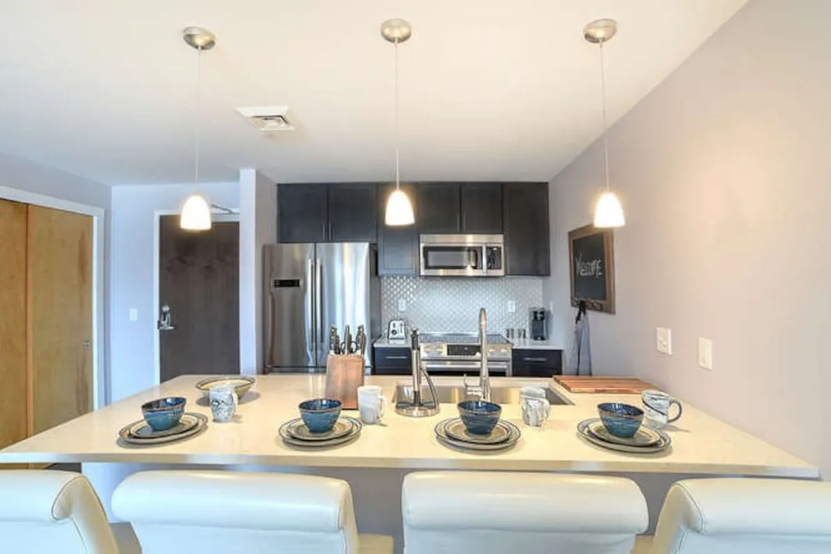 A striking kitchen with a central island, modern appliances, a thoughtfully set dining table, and elegant lighting fixtures. The setup creates a welcoming environment for shared meals, festive gatherings, and memorable evenings.